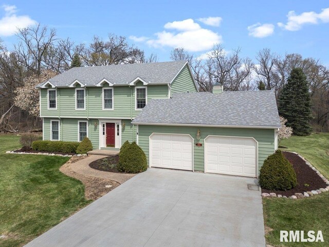view of front of home with a garage, driveway, and a front lawn
