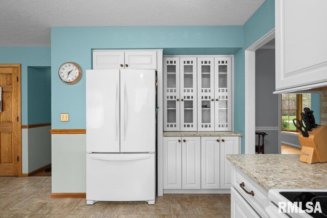 kitchen featuring a textured ceiling, white cabinets, white appliances, and glass insert cabinets
