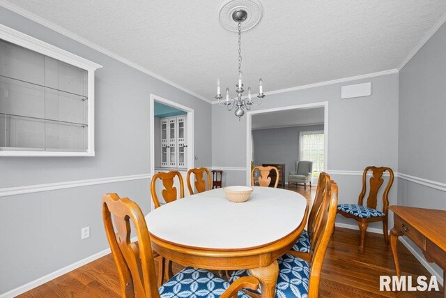 dining space with baseboards, a textured ceiling, wood finished floors, and a chandelier