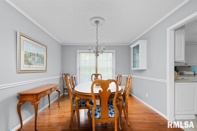 dining room with light wood-style floors, baseboards, crown molding, and a textured ceiling
