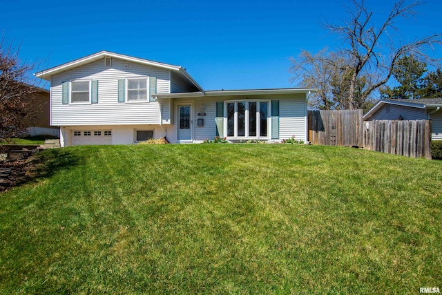 back of house with a lawn, fence, and an attached garage