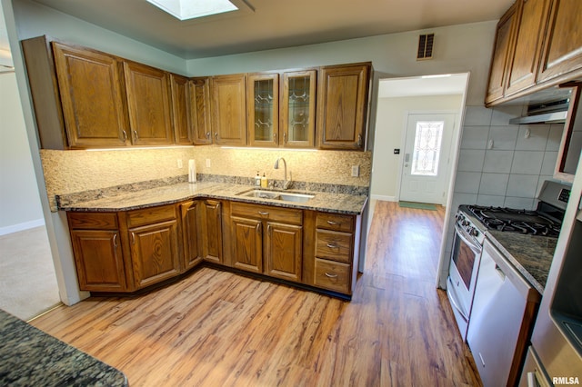 kitchen featuring brown cabinets, gas stove, a sink, and visible vents