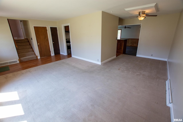 unfurnished living room featuring visible vents, baseboards, ceiling fan, carpet floors, and stairway