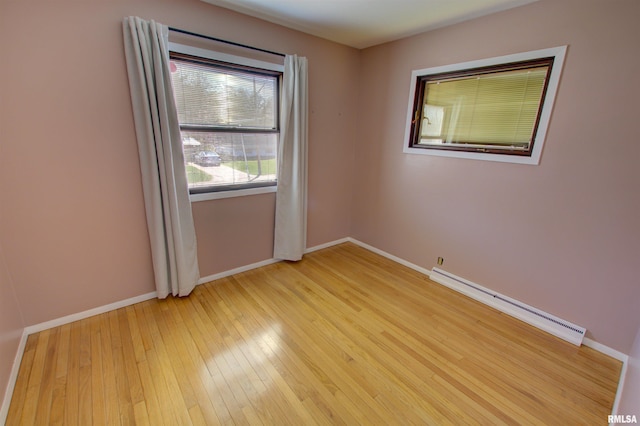 unfurnished room with a baseboard radiator, light wood-style floors, and baseboards