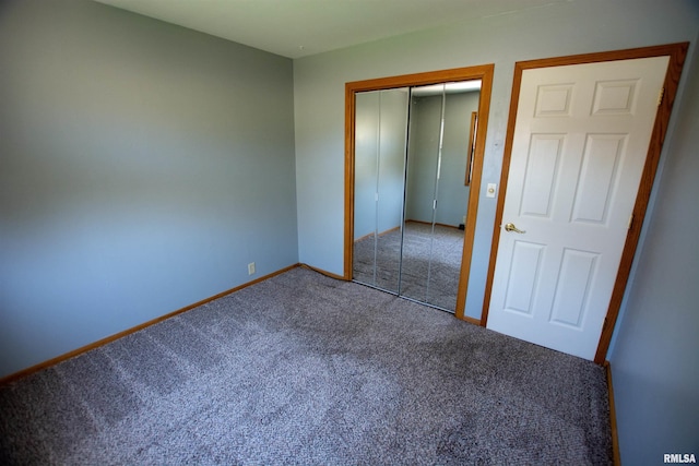 unfurnished bedroom with carpet, a closet, and baseboards