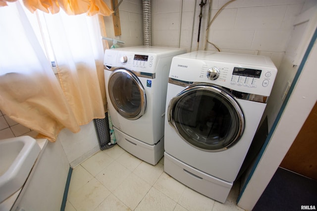 laundry area with washer and dryer, laundry area, light floors, and concrete block wall