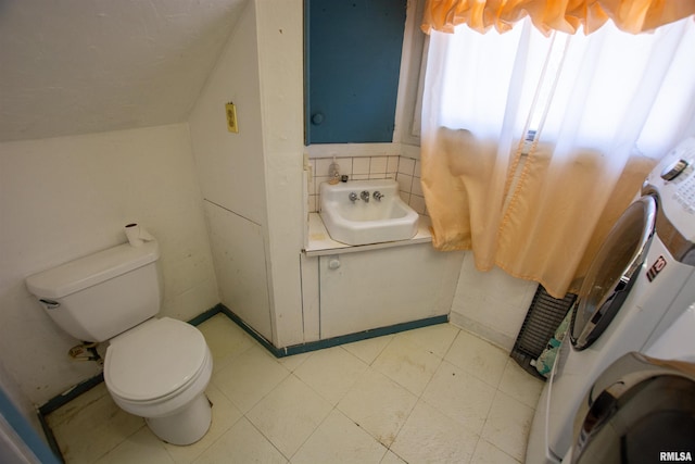 bathroom with a sink, tile patterned floors, toilet, and washer / dryer