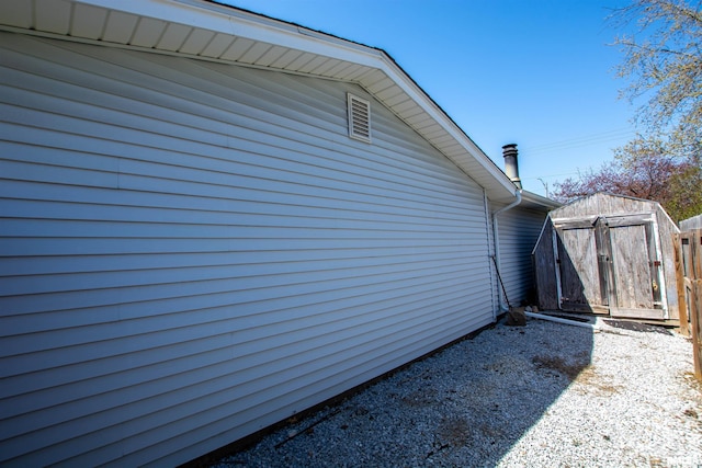 view of side of home featuring an outdoor structure, fence, and a storage unit