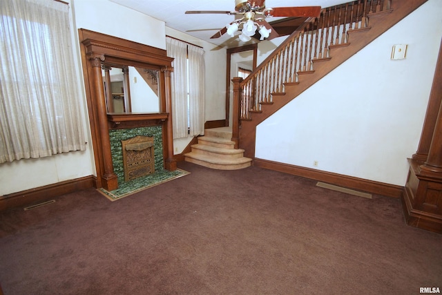 unfurnished living room with a fireplace, carpet, a ceiling fan, stairs, and baseboards