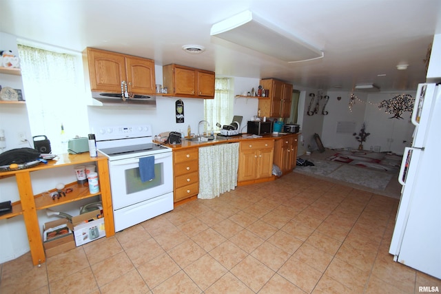 kitchen featuring visible vents, range hood, a sink, white appliances, and light tile patterned flooring