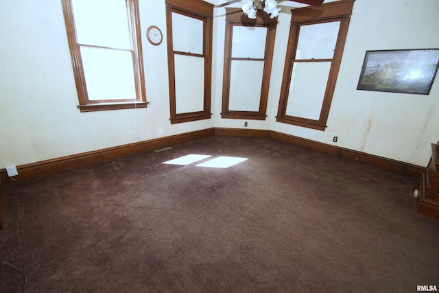 unfurnished room featuring dark carpet, baseboards, and a ceiling fan