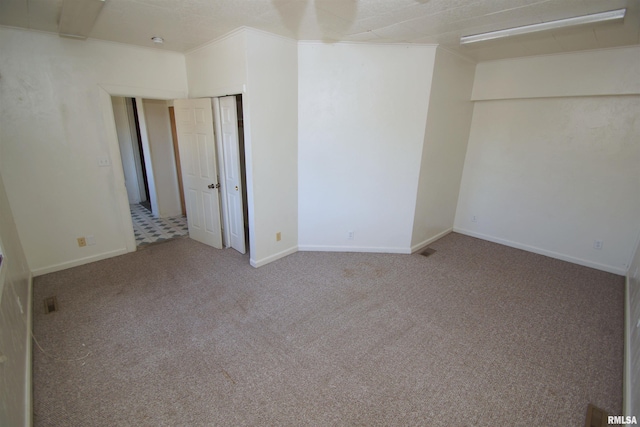 carpeted empty room featuring ornamental molding, visible vents, and baseboards