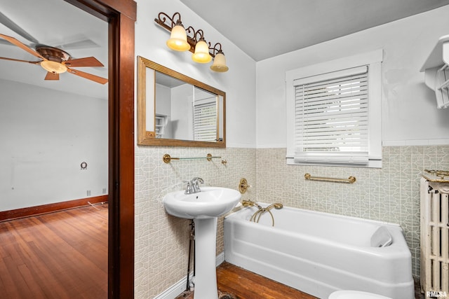 408 E Henry St, Atkinson, IL 61235 - bathroom featuring wainscoting, ceiling fan, radiator, a bath, and wood finished floors