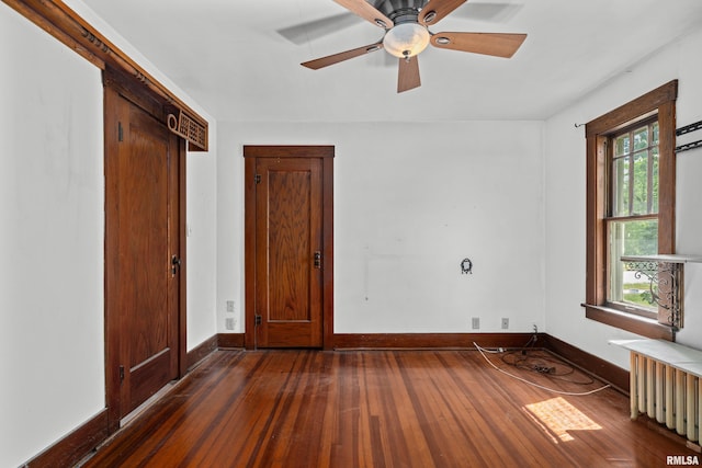 408 E Henry St, Atkinson, IL 61235 - unfurnished bedroom with dark wood-type flooring, baseboards, radiator, and ceiling fan