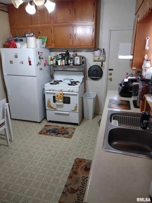 kitchen with light floors, white appliances, brown cabinets, ceiling fan, and a sink