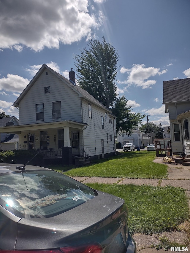 view of front of home featuring a chimney, a porch, and a front yard