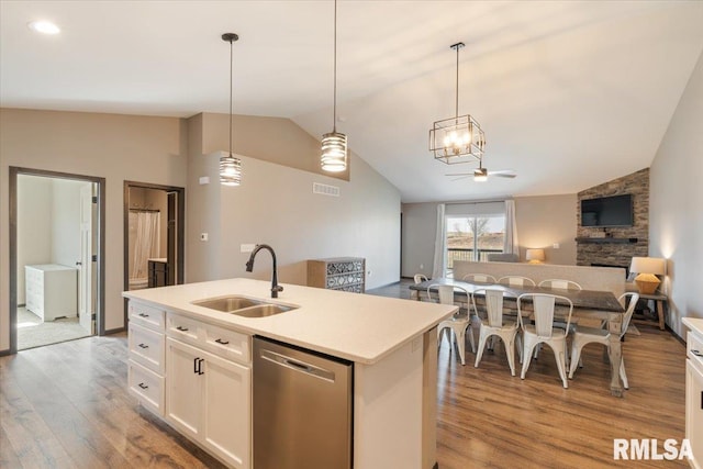 kitchen with dishwasher, a sink, open floor plan, light wood-type flooring, and lofted ceiling