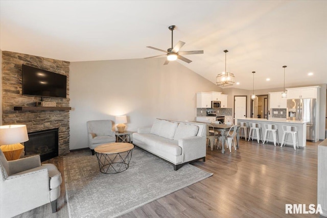living area with a ceiling fan, a fireplace, recessed lighting, vaulted ceiling, and wood finished floors