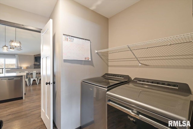 laundry area featuring laundry area, wood finished floors, separate washer and dryer, and a notable chandelier