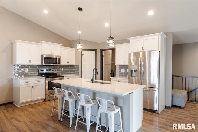 kitchen featuring tasteful backsplash, appliances with stainless steel finishes, an island with sink, and a sink