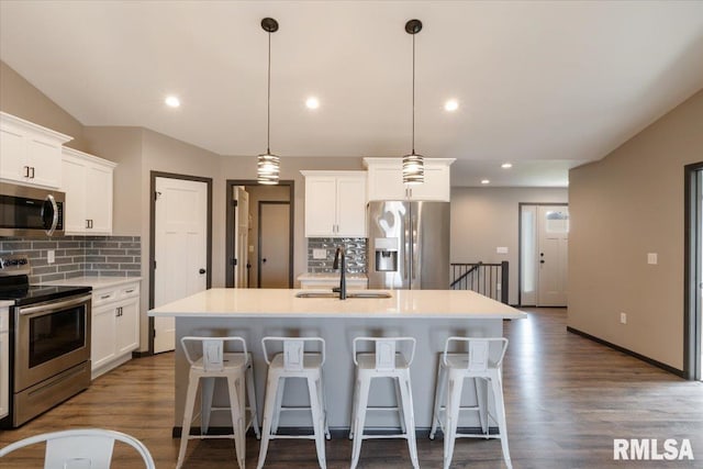 kitchen featuring stainless steel appliances, a breakfast bar, a sink, and decorative backsplash