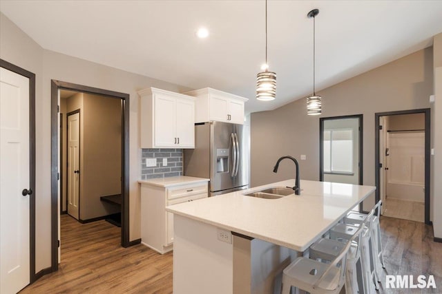 kitchen featuring light wood-style floors, white cabinetry, a kitchen island with sink, a sink, and stainless steel fridge