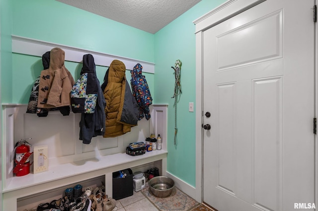 mudroom featuring a textured ceiling, baseboards, and tile patterned floors