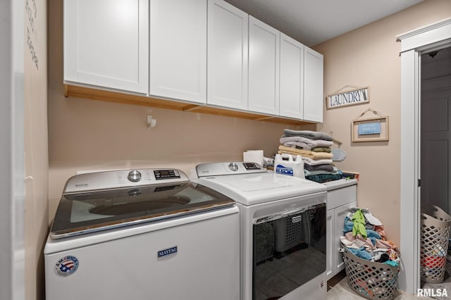 laundry room featuring washing machine and clothes dryer and cabinet space