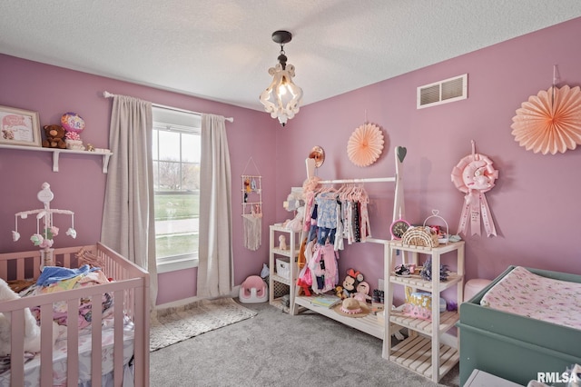 carpeted bedroom featuring a textured ceiling, visible vents, and a nursery area