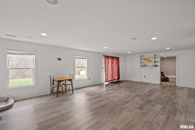 living area with a textured ceiling, wood finished floors, and visible vents
