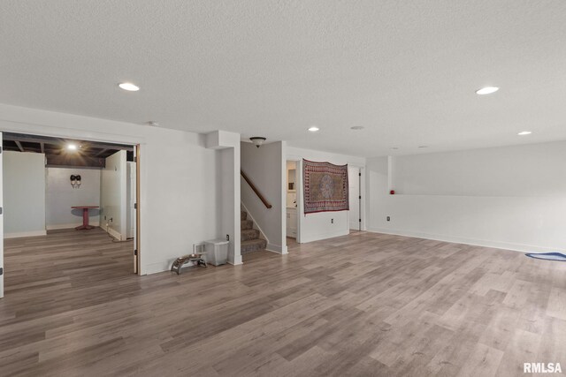 finished basement featuring wood finished floors, recessed lighting, baseboards, and stairway