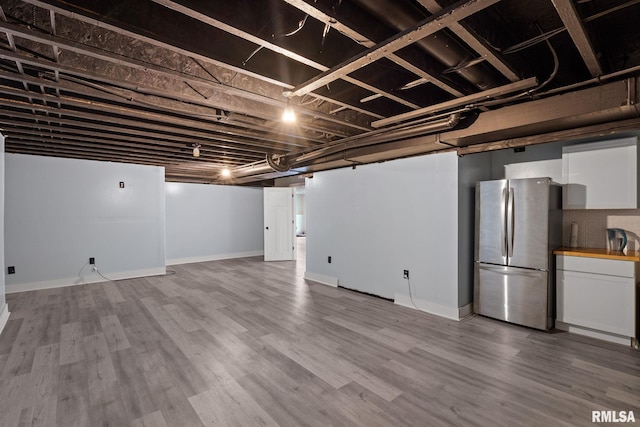 finished basement with baseboards, freestanding refrigerator, and wood finished floors
