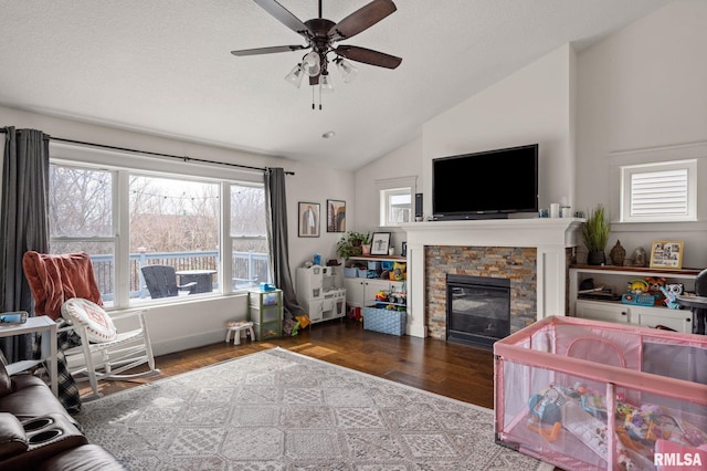 living area with wood finished floors, ceiling fan, a fireplace, and vaulted ceiling