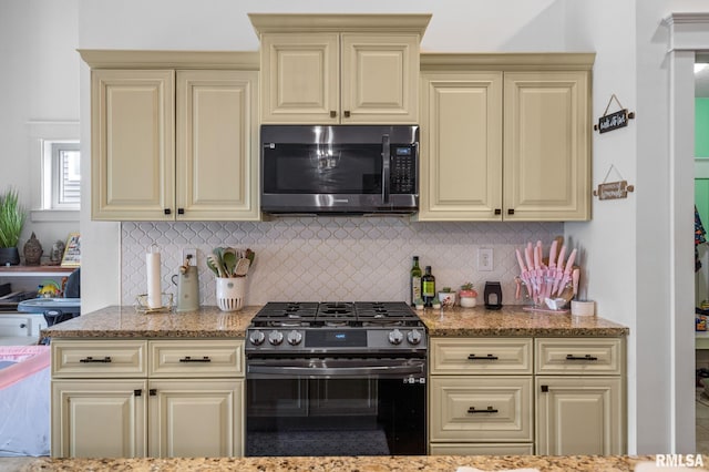 kitchen featuring stainless steel appliances, cream cabinets, and light stone counters