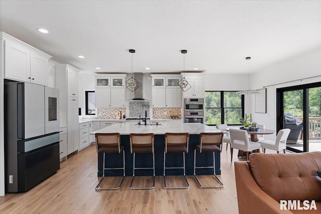 6817 Timber Ct, Bettendorf, IA 52722 - kitchen with freestanding refrigerator, wall chimney range hood, stainless steel double oven, light wood finished floors, and backsplash
