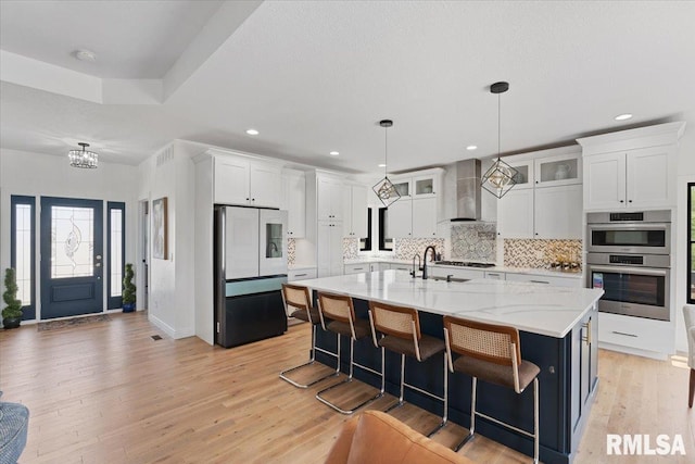 6817 Timber Ct, Bettendorf, IA 52722 - kitchen featuring refrigerator, wall chimney range hood, double oven, white cabinets, and decorative backsplash