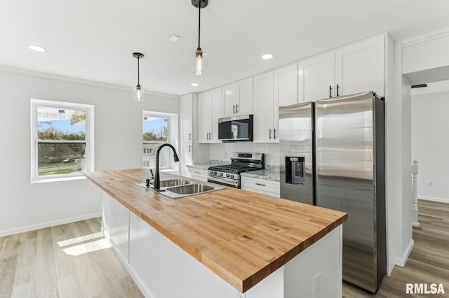 kitchen featuring light wood-type flooring, white cabinetry, butcher block counters, appliances with stainless steel finishes, and a sink