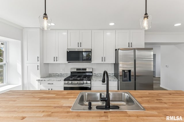 kitchen with wooden counters, a sink, backsplash, and appliances with stainless steel finishes
