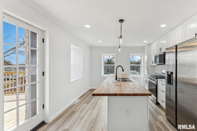kitchen featuring a sink, butcher block countertops, light wood-type flooring, and stainless steel appliances