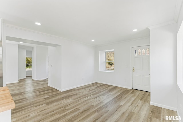 interior space featuring light wood finished floors, baseboards, and ornamental molding