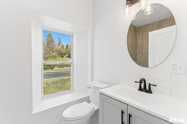 bathroom with tasteful backsplash, toilet, plenty of natural light, and vanity