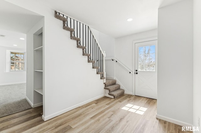 entryway featuring wood finished floors, baseboards, plenty of natural light, and stairs