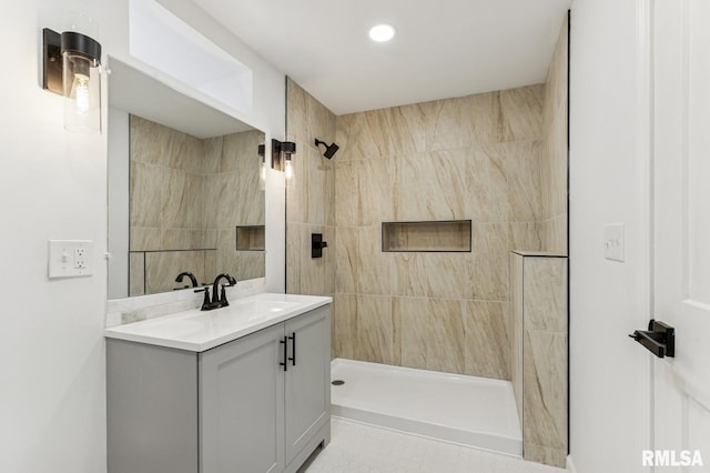 bathroom with tiled shower, vanity, and recessed lighting