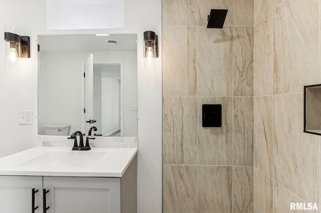 full bath featuring visible vents, toilet, tiled shower, and vanity