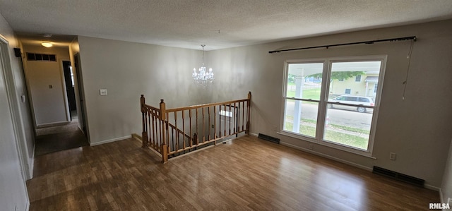 1606 Middle Rd, Camanche, IA 52730 - stairs with a chandelier, wood finished floors, healthy amount of natural light, a textured ceiling, and baseboards