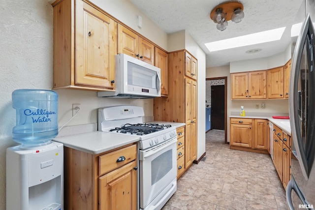 kitchen with light countertops, a skylight, and white appliances