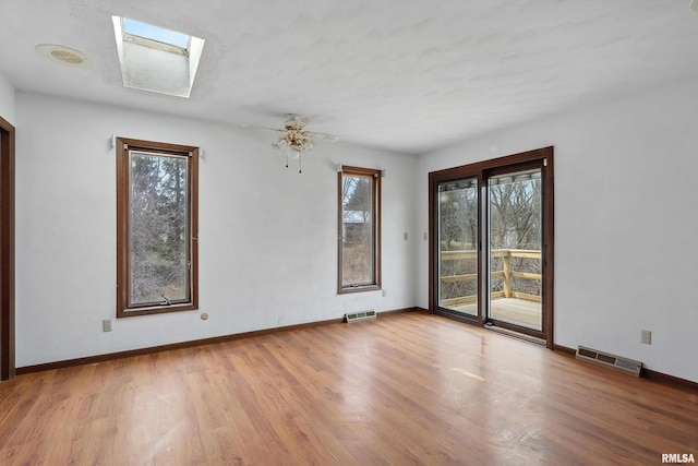 unfurnished room featuring visible vents, baseboards, a skylight, and wood finished floors