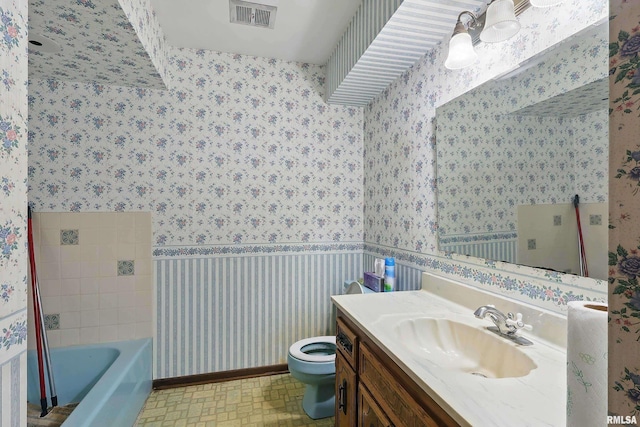 full bath featuring a bathing tub, vanity, visible vents, toilet, and wallpapered walls