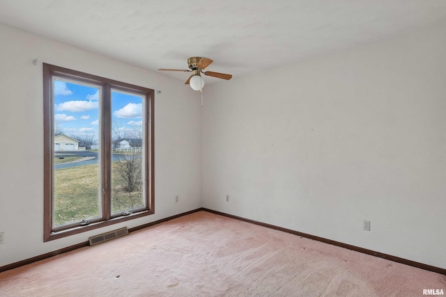 empty room with light carpet, visible vents, baseboards, and ceiling fan