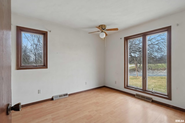 empty room with light wood finished floors, visible vents, baseboards, and a ceiling fan